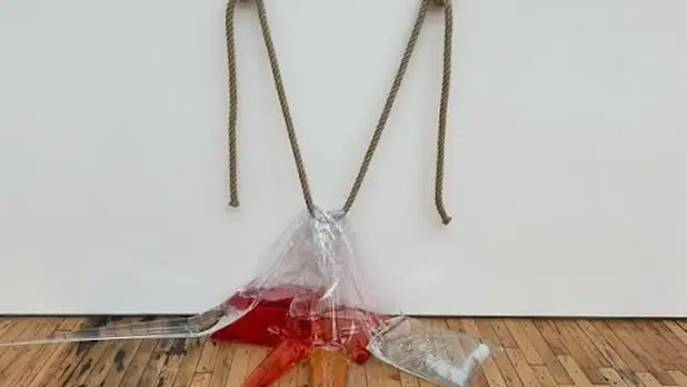 A rope holds up three clear plastic bags filled with red, orange, and clear liquid