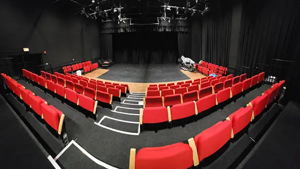 Rows of red upholstered seats inside the Ujima Theater