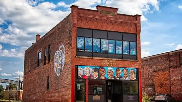 Mural of a row of 7 men and 1 woman on the brick exterior of the Colored Musicians Club in Buffalo.