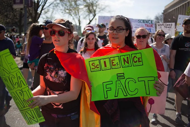 Protestors in Washington DC walk with signs and banners during the March For Science in 2018.