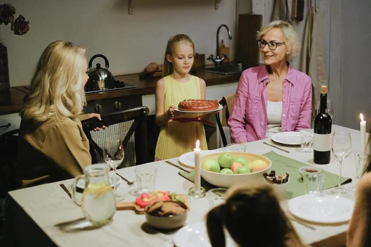 Girl serving a cake to her family at the dinner table