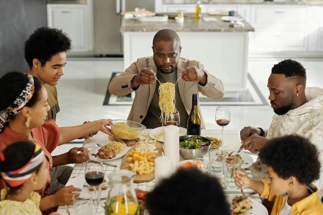 Family around table with father serving spaghetti