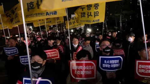 EPA Doctor protesters shout slogans and carry signs reading 'Opposition to the increase in medical schools' during a protest against the government's medical policy in Seoul