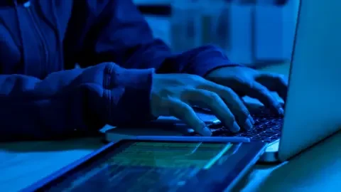 Getty Images A sinister image of a person's hands on a keyboard, with a tablet running some sort of code