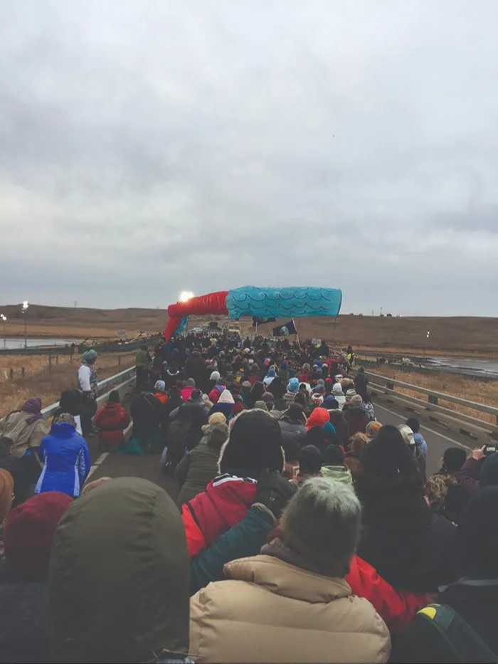 Crowd of people in sit-down protest on a road in the American west