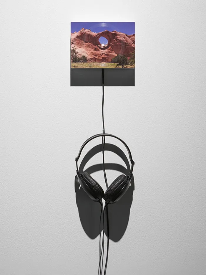 Headphones hanging on a wall below a picture of an American west rock formation