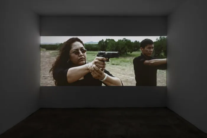 A gallery video shot of two Diné men aiming pistols at an unseen target