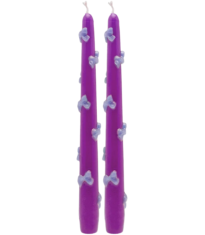 a pair of slender candles with 3D bows attached onto them 