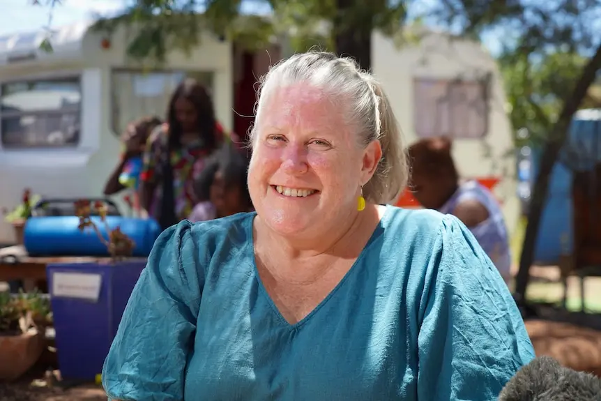 A woman in a blue shirt smiles at the camera