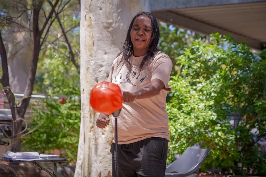 An Indigenous woman punches a punching bag