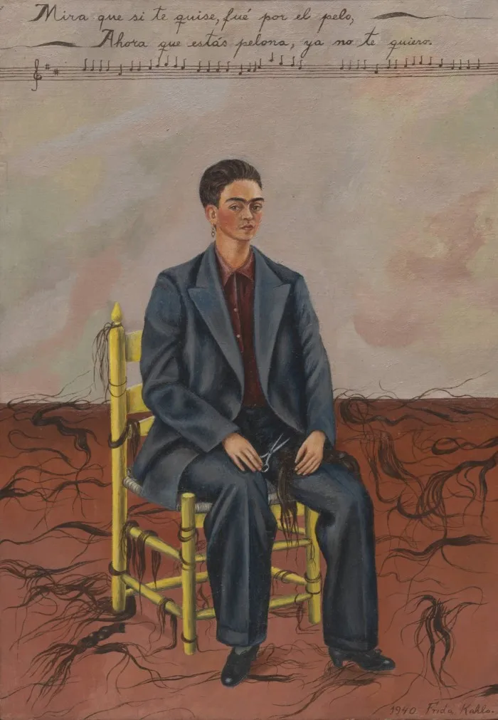Frida Kahlo’s ‘Self-Portrait with Cropped Hair’: the artist sitting on a chair, wearing a man’s suit, her hair short