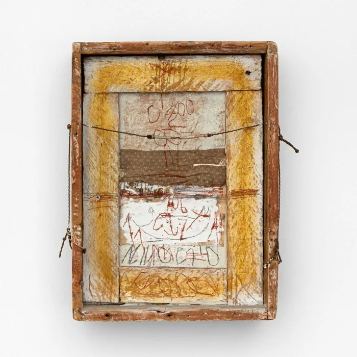 An artwork consists of a wooden box containing fabric, thread, and sheets of paper, painted and printed with scrawls and shapes