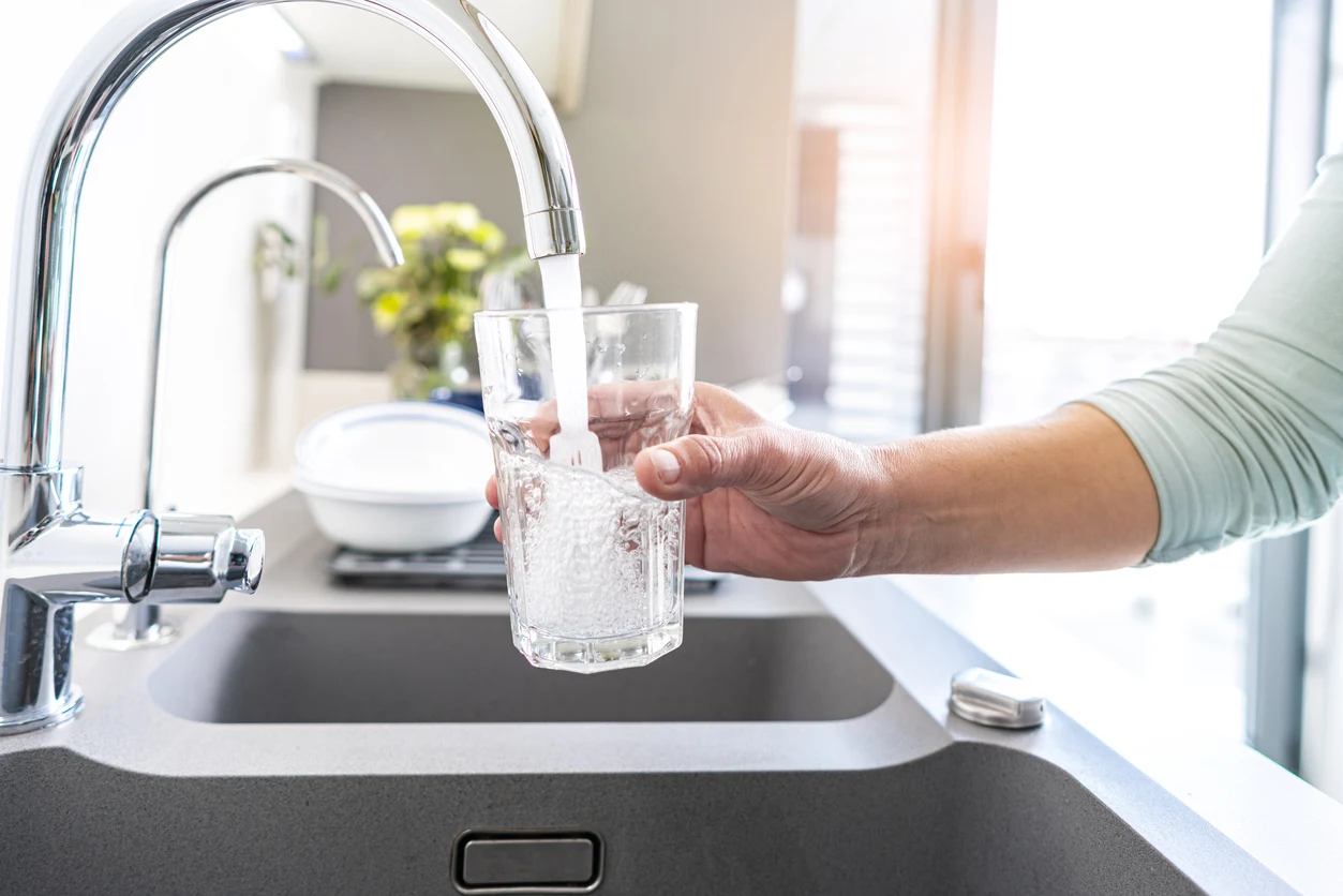 Close up of a person filling a glass with tap water from a sink faucet