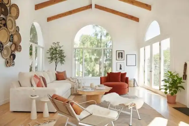 A view of a beautiful living room with white furniture and wooden accents. 