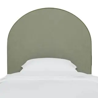 An olive green velvet arched headboard above a bed with all white bedding