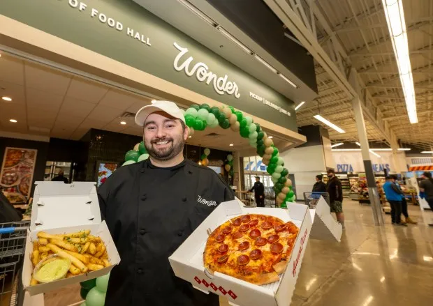 General Manager Zach Hein holds garlic fries from Fred's Meats & Bread and pepperoni pizza from Alanza Pizza on Wednesday, Feb. 21, 2024, at the new Wonder food hall inside the Walmart at Richland Crossings shopping center in Richland Township. Wonder offers food from eight different restaurants including Tejas Barbeque, Fred's Meats & Bread and Alanza Pizza. (April Gamiz/The Morning Call)