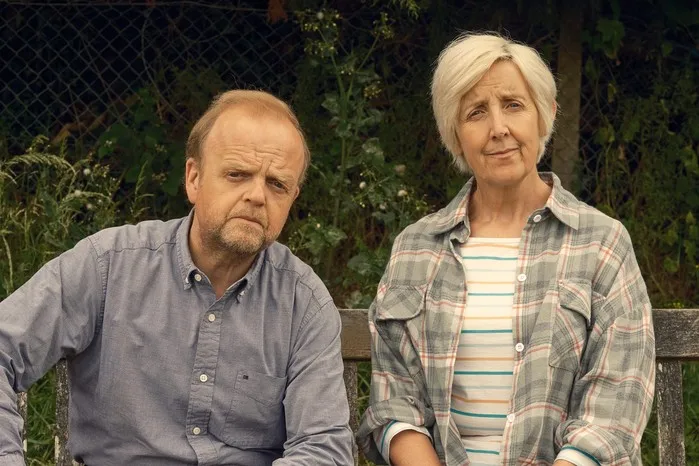 Toby Jones as Alan Bates and Julie Hesmondhalgh as Suzanne in Mr Bates vs the Post Office sitting on a wooden bench