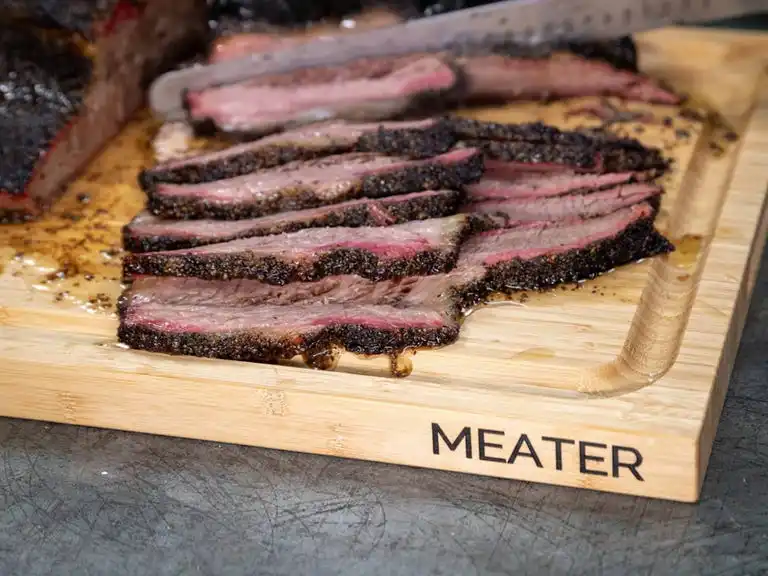 cutting board with meat sliced on top