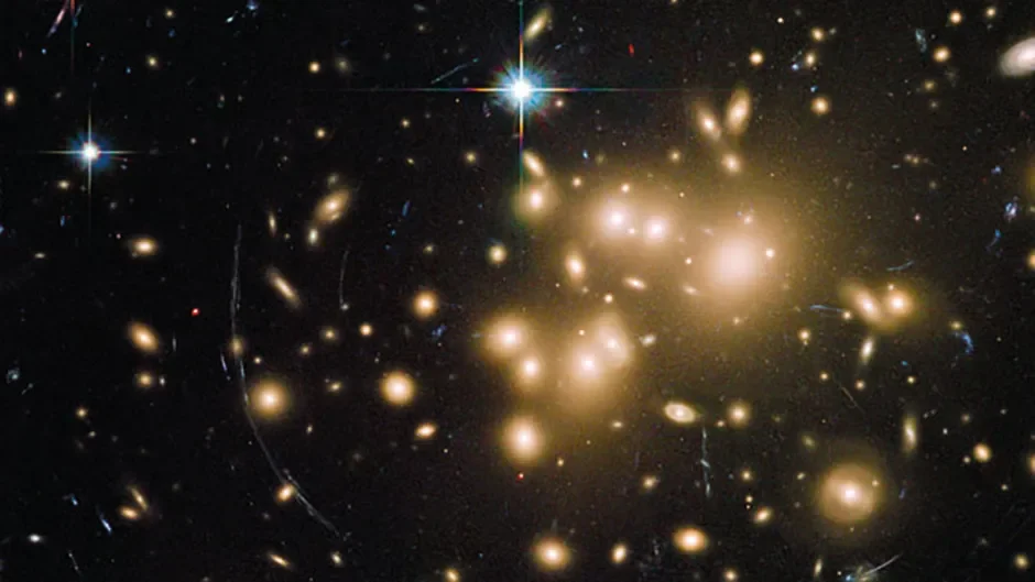 A Hubble Space Telescope image showing gravitational lensing. At the centre of the image is a galaxy cluster that has so much dark matter mass its gravity is bending the light of more distant objects (seen as curves of light. Credit: NASA, ESA, J. Richard (CRAL) and J.-P. Kneib (LAM). Acknowledgement: Marc Postman (STScI)