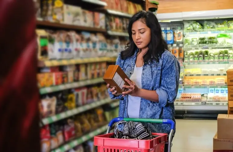 Portrait shot of Southeast Asian woman reading nutrition label on cereal packaging during her weekly shopping in the supermarket.