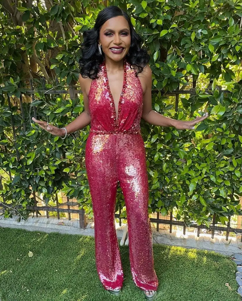 mindy kaling red sequin jumpsuit posing in garden