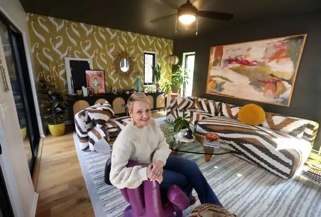 Laura Seymour sits in a purple hand-shaped chair in her Irondequoit living room.