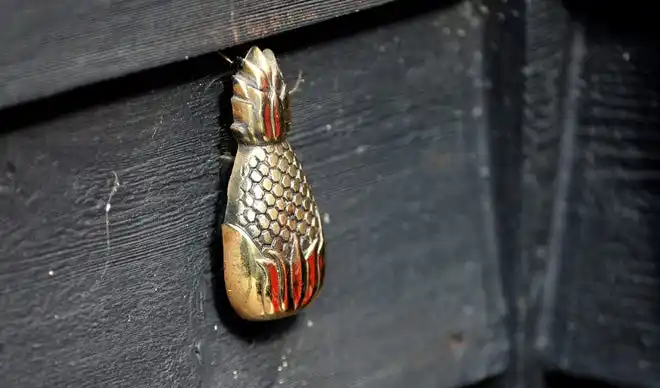 A brass pineapple-shaped doorbell welcomes guests.