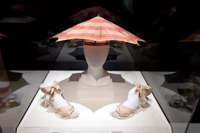 A display case with a vintage sunshade hat and sandals. The newest exhibit at The Cummer Museum of Art and Gardens, Sporting Fashion: Outdoor Girls 1800 to 1960 opened Wednesday, February 28, 2024. The exhibit is made up of 65 ensembles of women's clothing and other related accessories designed, starting in the early 1900s to simply allow women to get outside to walk and garden and as more opportunities opened up, more activity specific clothing was designed with Western cultural expectations taken into account. The exhibit was organized by the American Federation of the Arts and FIDM Museum of the Fashion Institute of Design & Merchandising in Los Angeles.