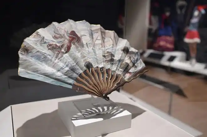 A vintage fan with ocean swimming and diving scenes printed on it. The newest exhibit at The Cummer Museum of Art and Gardens, Sporting Fashion: Outdoor Girls 1800 to 1960 opened Wednesday, February 28, 2024. The exhibit is made up of 65 ensembles of women's clothing and other related accessories designed, starting in the early 1900s to simply allow women to get outside to walk and garden and as more opportunities opened up, more activity specific clothing was designed with Western cultural expectations taken into account. The exhibit was organized by the American Federation of the Arts and FIDM Museum of the Fashion Institute of Design & Merchandising in Los Angeles.