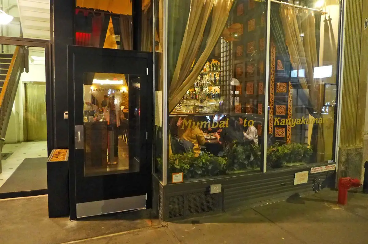 A darkened storefront with a bar and bottles visible through the window.