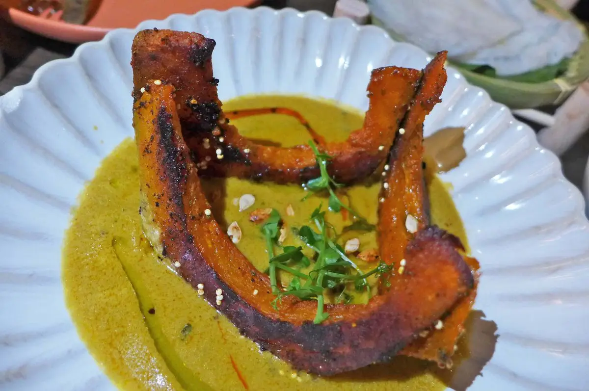 Big arcs of pumpkin sticking up from a yellowish sauce.