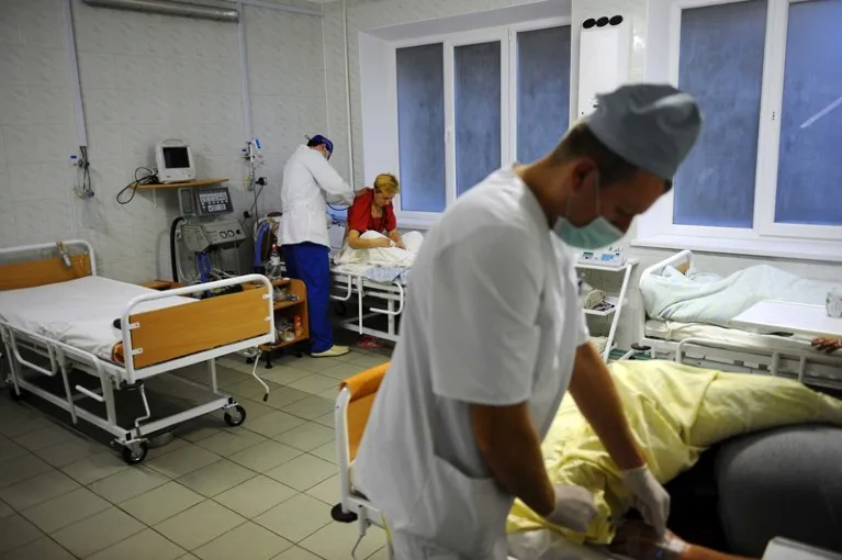 A doctor places a stethoscope on a patient's back in a hospital