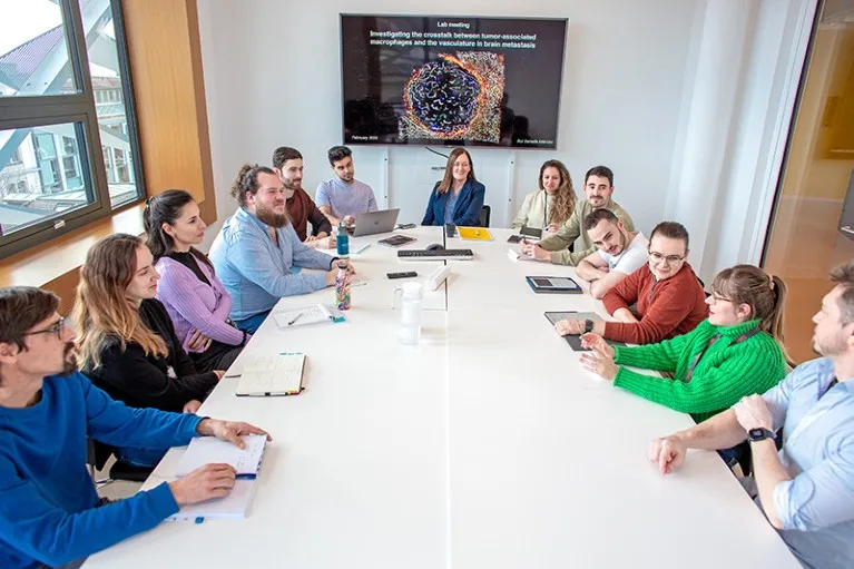 Johanna Joyce and her lab members during the flashlight part of their group meeting around a conference table.