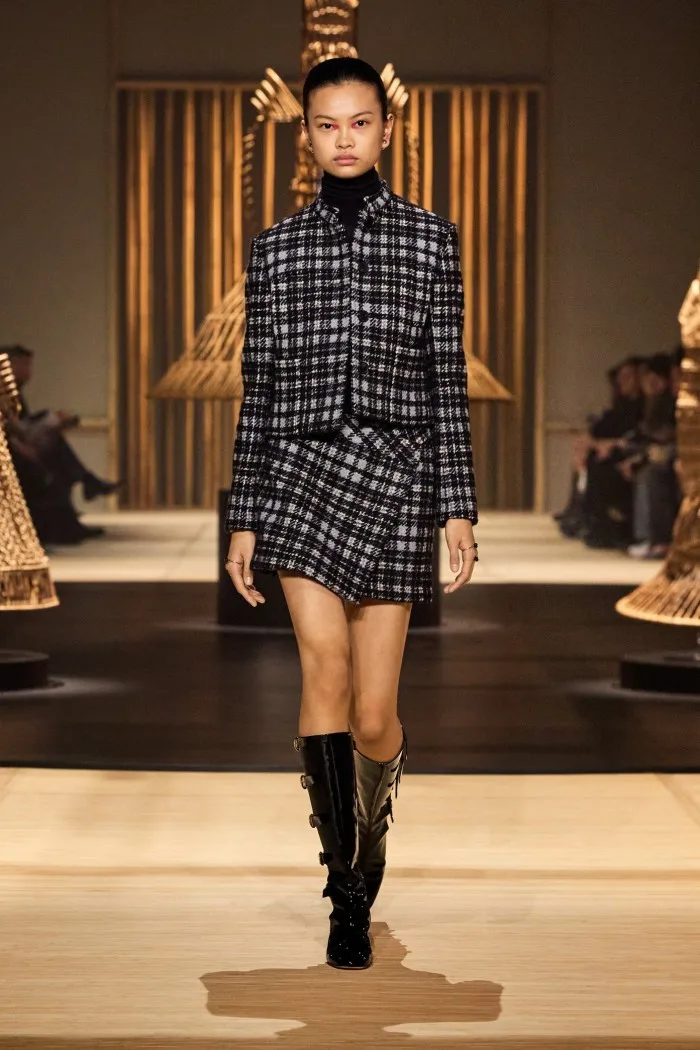 A model wears a check suit jacket and matching miniskirt with black boots