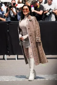 PARIS, FRANCE - JULY 06: Huda Kattan wears a cream lace long sleeves top, cream mini skirt, logo print tights, cream boots and Fendi logo printed coat, outside Fendi, during the Haute Couture Fall/Winter 2023/2024 as part of  Paris Fashion Week on July 06, 2023 in Paris, France. (Photo by Claudio Lavenia/Getty Images)