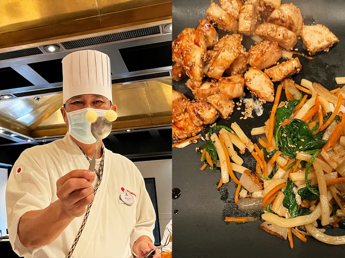 Hibachi chef making Mickey Mouse ears with butter and spoon, plate of chicken, noodles, and vegetables.