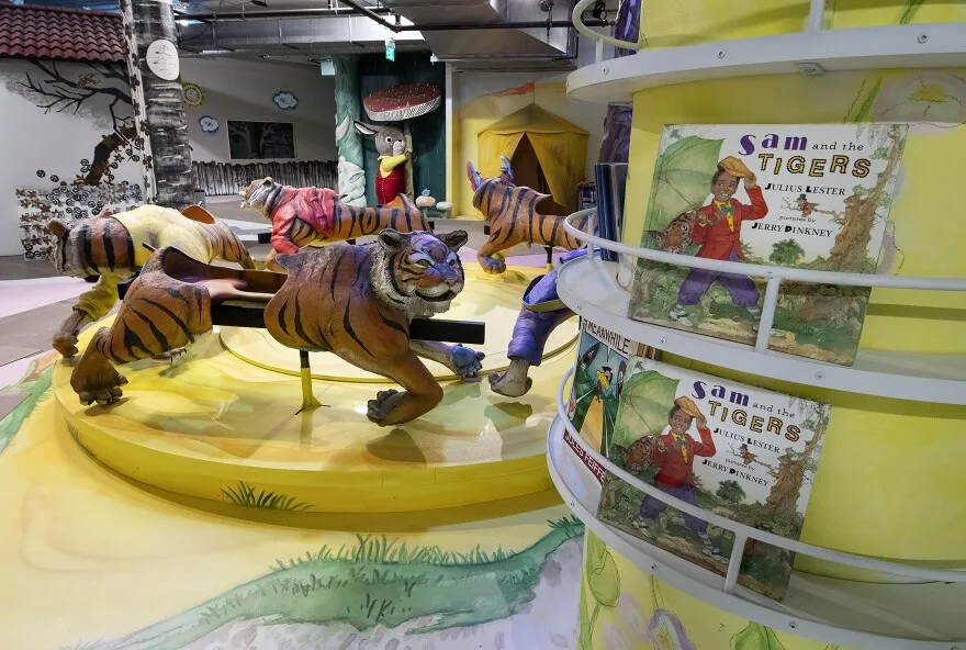 Each exhibit includes shelves for books to read much like these in an exhibit still in progress based on “Sam and the Tigers,” the book by Julius Lester.