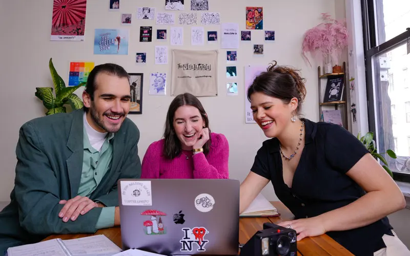 Three people look at a computer