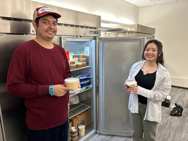 Students Jose Escalante and My Ly hold some of the prepared meals in the Stock Up for Success Food Pantry on Blue Bell Campus created using excess foods from the Culinary Arts program. The new meal preparation initiative is called the Food Recovery Program. (Photo by Eric Devlin)