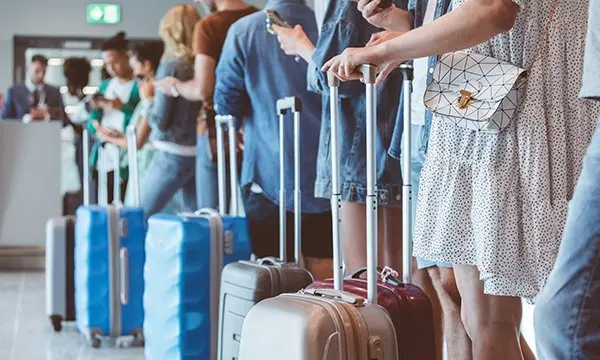 A line of people with suitcases queuing to show their documents at an airport