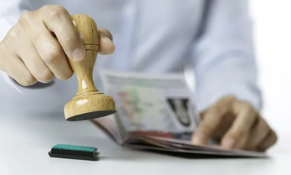 An immigration official holding an official seal ready to stamp a passport