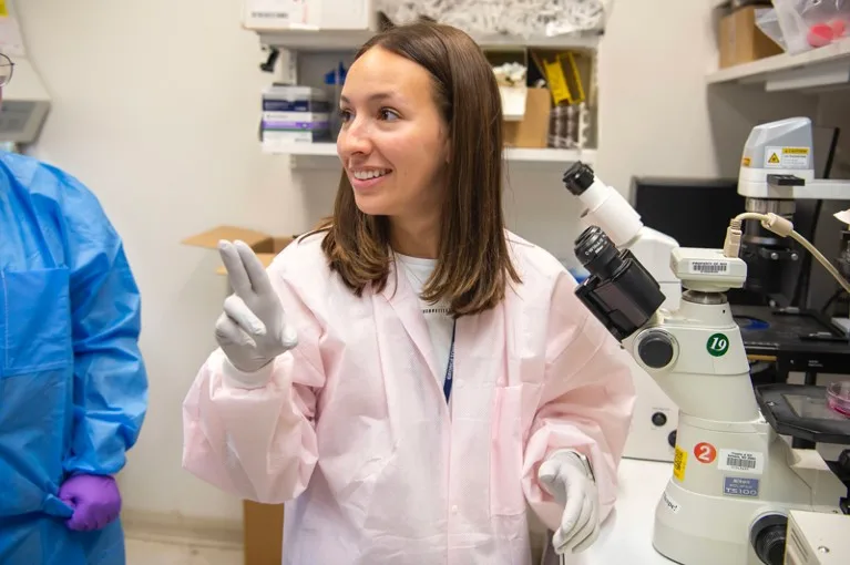 Megan Majocha signing next to a microscope in the lab