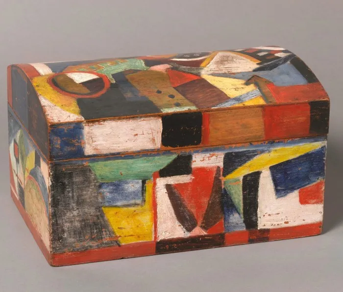 Wooden chest covered in faded paint in random geometric patterns in different colours