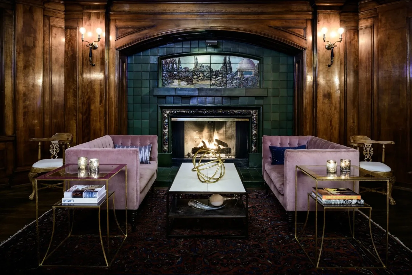 Two violet-colored sofas facing each other next to green-tiled fireplace in lounge at Sorrento Hotel 