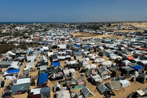 An overhead view of many tents on sand.