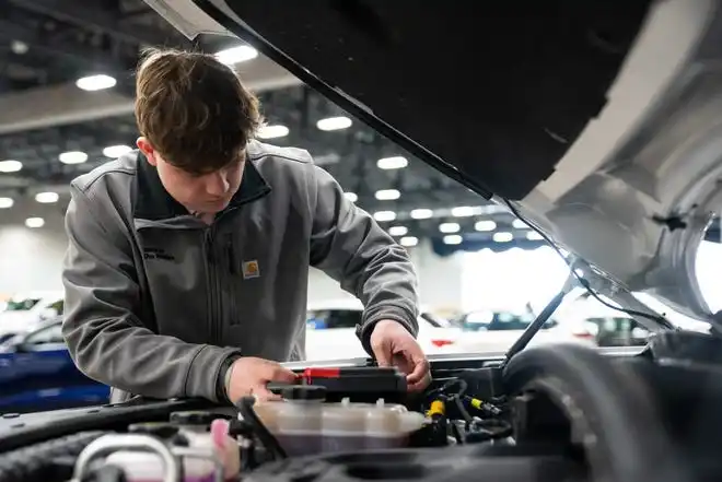 Karsen Shelburg checks the engine of one of his dealership's BMWs Thursday, March 14, 2024, at the Iowa Events Center.