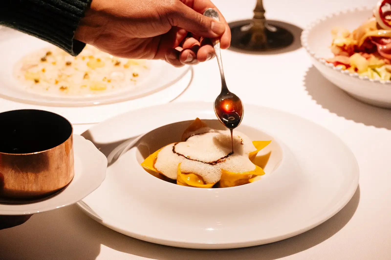 Tortellini with a spoon drizzling sauce over the top.