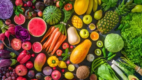 Colorful raw fruits and vegetables varied vegan food, vivid rainbow arrangement