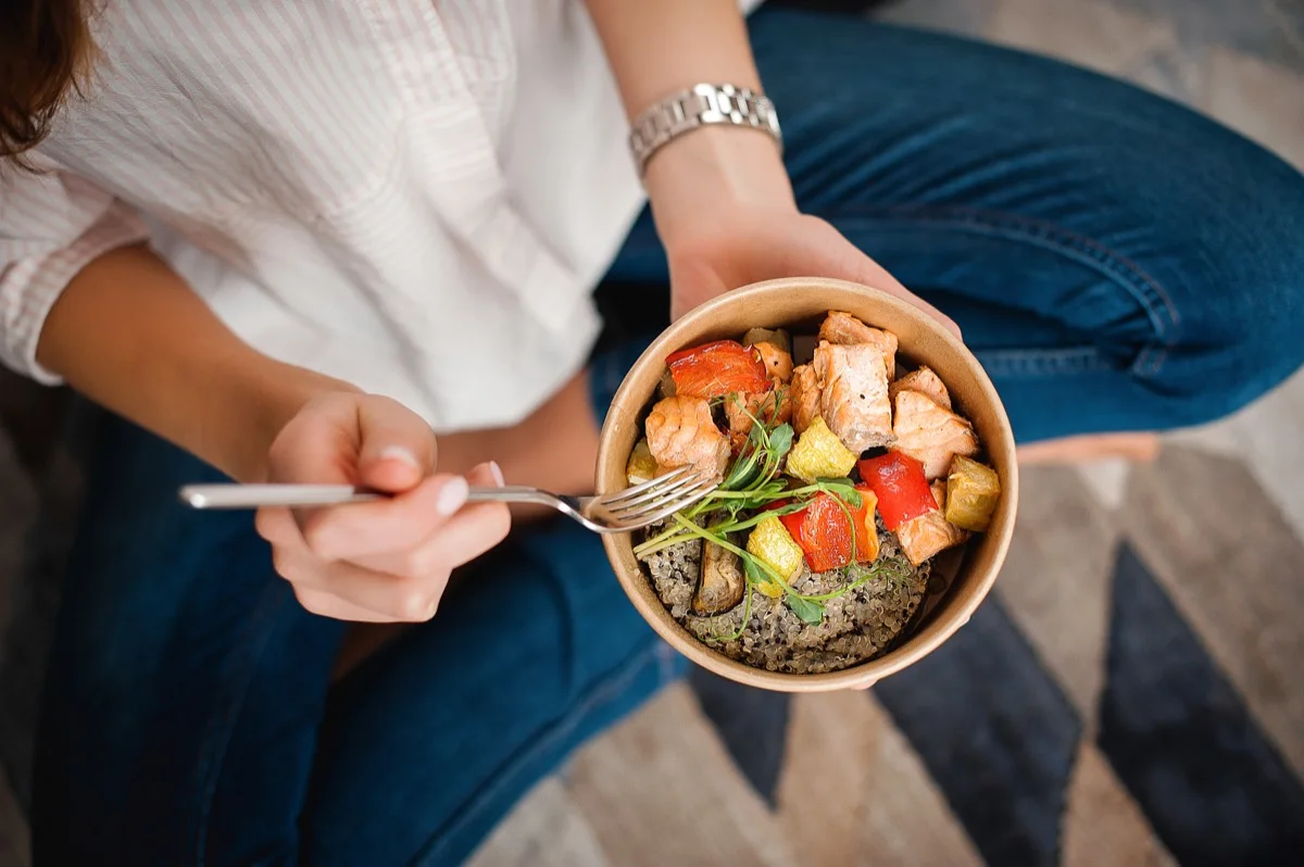 Closeup of woman eating small bowl of healthy food