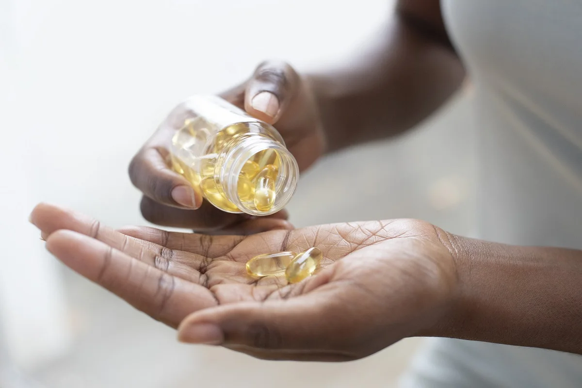 A close-up of a woman pouring capsules into her hand.